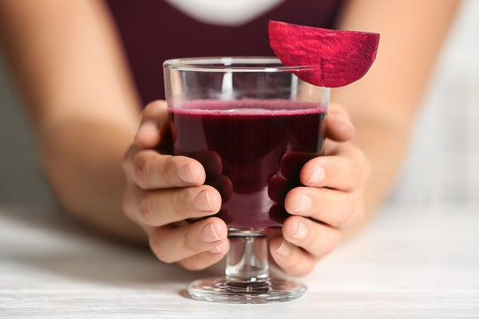 Woman with glass of beet smoothie at table, closeup
