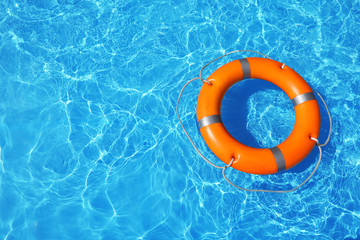 Lifebuoy floating in swimming pool on sunny day, top view with space for text