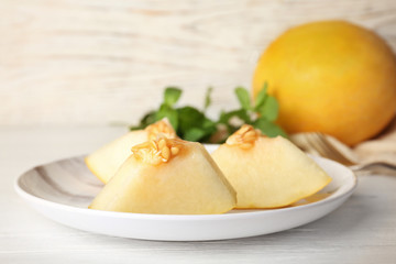 Plate with cut sweet melon on table