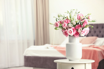 Vase with beautiful flowers on table in bedroom, space for text