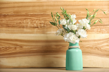 Vase with beautiful flowers on table against wooden background, space for text