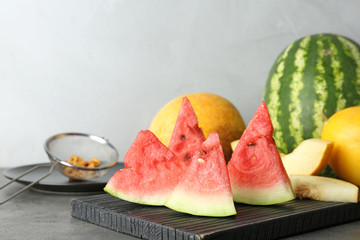 Watermelon and melon slices on cutting board against light background