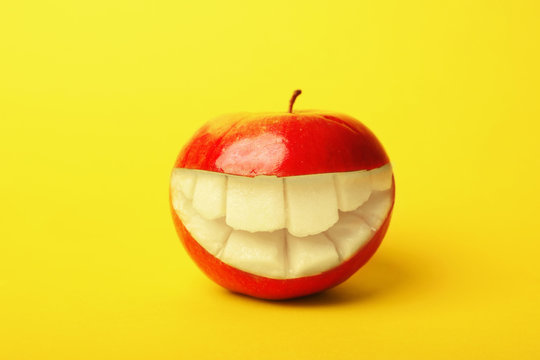 Funny smiling apple on color background