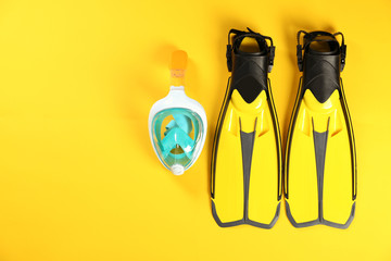 Swimming flippers and mask on color background, top view. Space for text