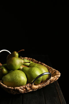 Tray with ripe pears on wooden table against dark background. Space for text