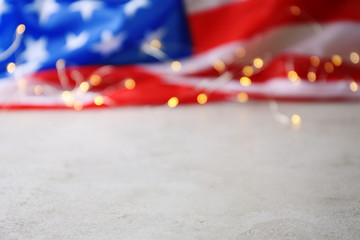 Blurred American flag and garland on grey table. Space for text
