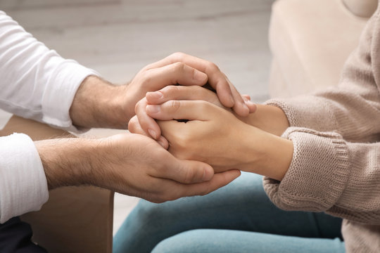 Man holding woman's hands indoors, closeup. Concept of support and help