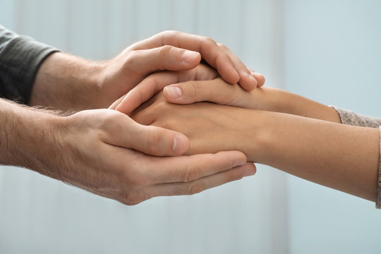 Man holding woman's hands against blurred background, closeup. Concept of support and help