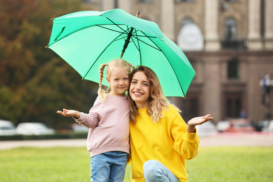 Happy mother and daughter with umbrella in park