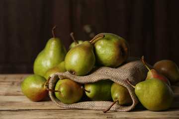 Fresh ripe pears on wooden table against dark background