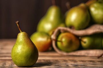 Fresh ripe pear on wooden table against blurred background