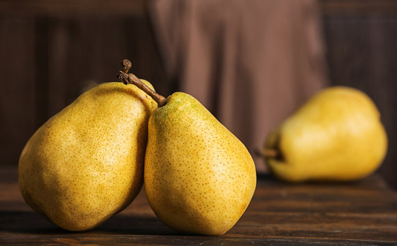 Fresh ripe pears on wooden table against blurred background