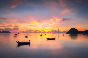 Thai fishing boat used as a vehicle for finding fish in the sea.at sunrise. Beautiful sunrise over an old wooden fishing boat on a pebble beach in Prachuap Khiri Khan,  Thailand.
