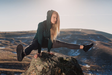 Young fit woman exercising on a mountain top