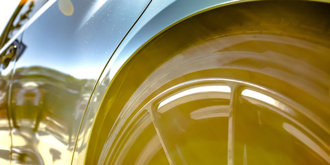 Tire rim and side exterior of a buffed blue car