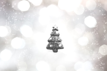 キラキラなシルバーと黒と白のボケ背景の真ん中に黒のクリスマスツリーの輪郭