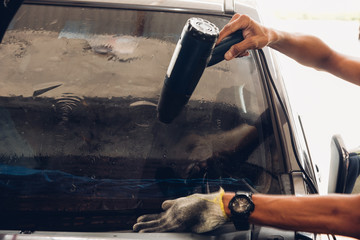 Man specialist attached window film by hot gun on car