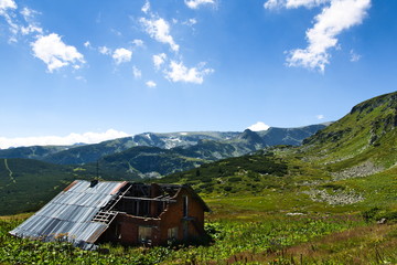 abandoned house in the mountains against a brilliant blue sky