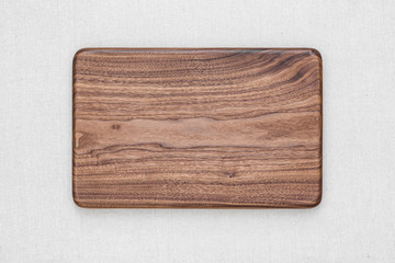 Handmade black walnut rectangular chopping board on burlap, walnut texture background