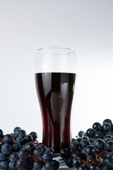 glass of the grape juice with grape branchs on the white backround