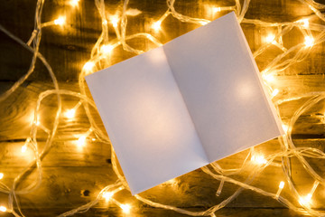Blank paper and christmas lights on vintage wooden background