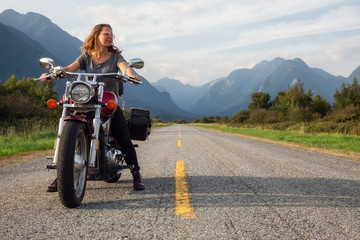 Woman riding a motorcycle on a scenic road surrounded by Canadian Mountains. Taken in Pitt Meadows,...