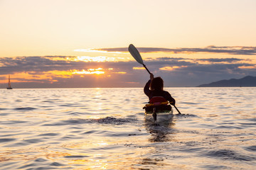 Girl Sea Kayaking during a vibrant sunny summer sunset. Taken in Vancouver, BC, Canada.
