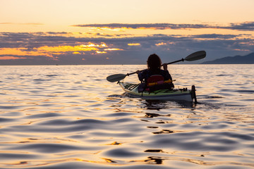 Girl Sea Kayaking during a vibrant sunny summer sunset. Taken in Vancouver, BC, Canada.