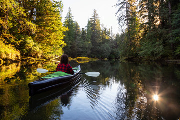 Fototapeta premium Girl kayaking in the beautiful river during a sunny summer morning. Taken in San Josef Bay, Cape Scott, Northern Vancouver Island, BC, Canada.