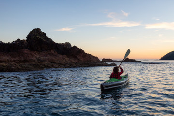 Girl kayaking in the Pacific Ocean during a cloudy summer sunset. Taken in San Josef Bay, Cape Scott, Northern Vancouver Island, BC, Canada.