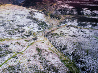 Aerial view looking across a valley on mountain range in the UK. Taken around dusk on a wintery day by drone showing amazing textures