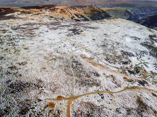 Aerial view looking straight down on a snowy mountain range hikers trail in the UK. Satellite style view, taken around sunset on a wintery day by drone showing incredible landscape textures and colour