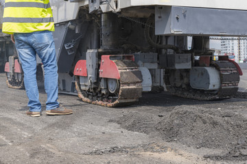 Close view on the workers and the asphalting machines. Machinery for asphalting roads