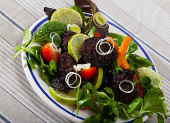 Fried tasty  blood sausage with lettuce and lemon, served at plate
