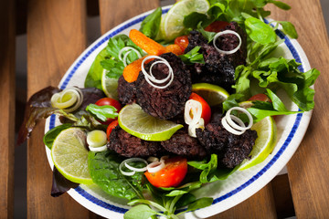 Prepared tasty blood sausage with  lettuce and lemon served at plate