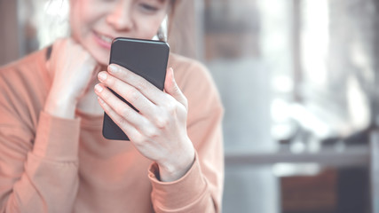 Happy female using smartphone at modern coffee shop, she working or playing social network on mobile.