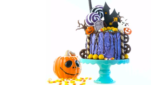 On trend Halloween candyland fantasy novelty drip cake on white background.