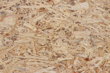 Fiberboard. Compressed light brown wooden plywood texture. Close up surface of pressed wood-shaving plate. Old wooden board bagasse background. Prefabricated plate made of sawdust.