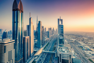 Skyscrapers and highways of a big modern city at sunset. Aerial view on downtown Dubai, United Arab Emirates. - obrazy, fototapety, plakaty