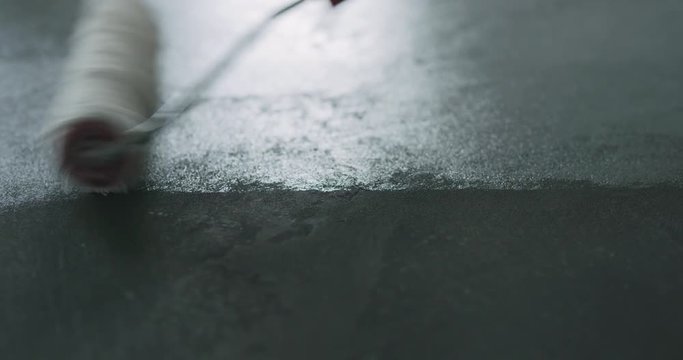 Slow motion handheld closeup applying protective coating on the concrete floor