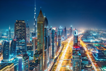 Spectacular urban skyline with colourful city illuminations. Aerial view on highways and skyscrapers of Dubai, United Arab Emirates. - obrazy, fototapety, plakaty