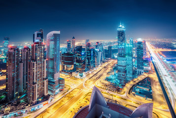 Obraz premium Spektakularna miejska panorama z kolorowymi iluminacjami miasta. Widok z lotu ptaka na autostrady i drapacze chmur w Dubaju, w Zjednoczonych Emiratach Arabskich.
