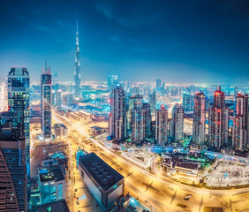 Fototapeta na wymiar Spectacular urban skyline with colourful city illuminations. Aerial view on highways and skyscrapers of Dubai, United Arab Emirates.
