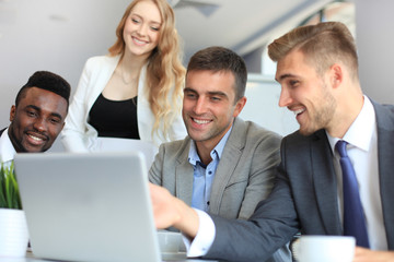 Brainstorm. Group of business people looking at the laptop together. One business woman looking at camera.