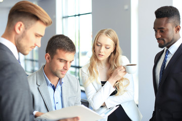 Fototapeta premium Young modern colleagues in smart casual wear having a brainstorm meeting while standing in the creative office.