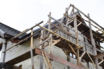 Wooden scaffolding next to white residental house built of aerated concrete blocks  with grey...