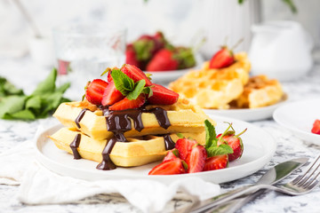 Belgium waffles with chocolate topping and strawberries. Breakfast food