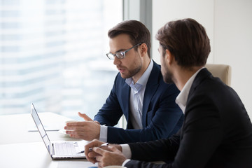 Focused male colleagues or partners discuss future business project negotiating during office...