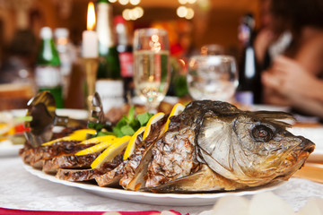 Fried sliced stuffed fish dressed with sliced lemon slices on a served table in a restaurant
