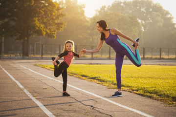 Mom and daughter on the morning sports training do a warm-up